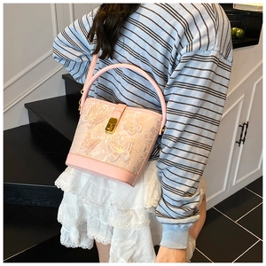 Sac seau rose en dentelle avec appliques papillons porté par un mannequin