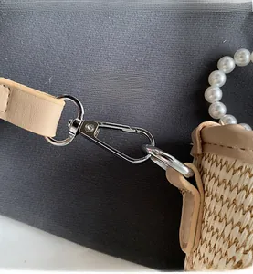 Détail du sac tressé montrant le fermoir argenté, la garniture cuir et l'anse en perles
