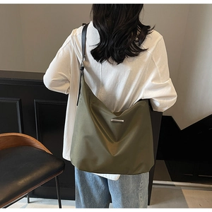 Detail view of large olive green tote bag featuring shiny fabric and silver metal hardware