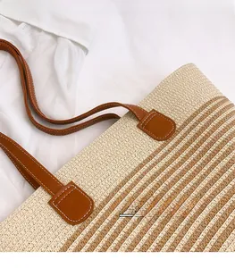 Détail du sac cabas tissé avec anses en cuir marron et surpiqûres blanches contrastées