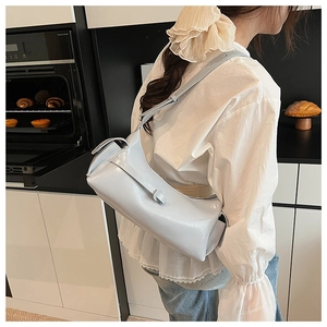 Detailed side view of a light gray slouchy dumpling shoulder bag worn by a model