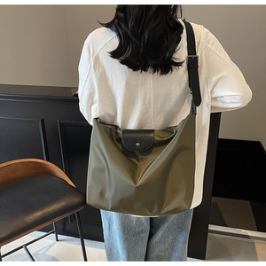Detail view of large olive green nylon tote bag with leather flap and black strap