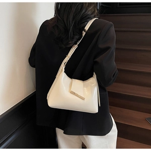 Modell mit cremeweißer Umhängetasche aus glänzendem Kunstleder mit elegantem Metalldetail