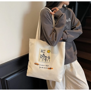 Detail of minimalist cream canvas tote bag with graphic print worn by a person