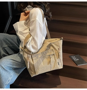 Close-up of khaki nylon tote bag featuring multi-pocket design and woven rope zipper pulls