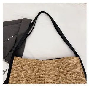 Gros plan sur un sac cabas en paille tressée avec de fines anses en cuir noir nouées