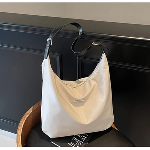 Detail of cream nylon hobo bag with adjustable black leather strap and silver logo bar