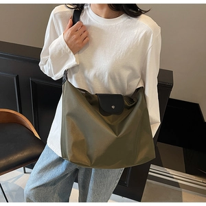 Olive green nylon tote bag featuring black leather flap detail and wide shoulder strap