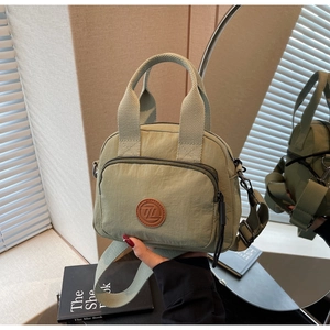 Details der salbeigrünen Nylon-Umhängetasche mit Lederlogo und verstellbarem Gurt