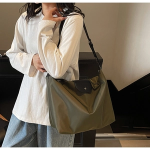 Detail of olive green nylon tote bag with black leather flap and shoulder strap