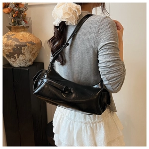 Detail of black glossy patent leather shoulder bag with buckle and adjustable strap
