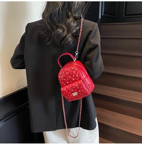 Red quilted mini backpack with rhinestones and metal chain on model with black suit