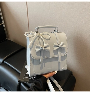 Détail d'un sac à dos bleu clair avec des nœuds mignons et des perles blanches décoratives