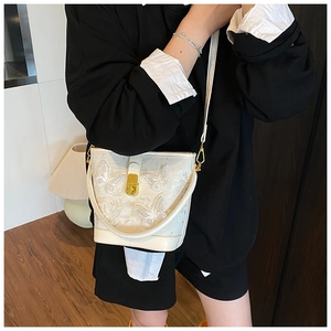 Détail du sac seau blanc avec broderie papillon 3D et fermoir en métal doré brillant
