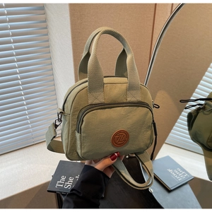 Makroansicht der salbeigrünen Nylontasche mit Leder-Logo und verstellbarem Riemen