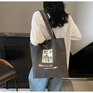 Detail view of dark grey canvas tote bag featuring literary graphic print and orange text
