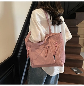 Detail of pink nylon tote bag with multiple zippers and woven pullers on shoulder strap