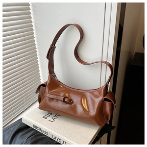Detail view of a vintage brown glossy PU leather shoulder bag with buckle and side pockets