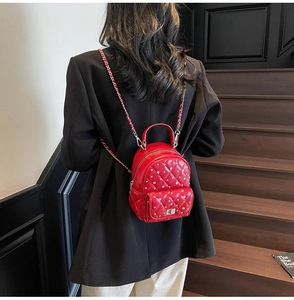 Mini red quilted backpack with pearls and chain strap shown on a black suit blazer