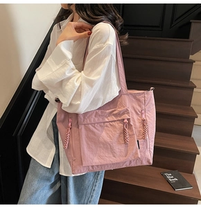 Pink nylon tote bag detail with side zipper pocket and braided puller on model