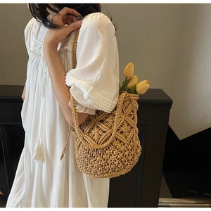 Close-up of beige handmade hollow-out woven shoulder bag with chic tassel details