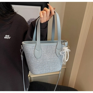 Détails d'un sac cabas tressé bleu et blanc avec des breloques élégantes