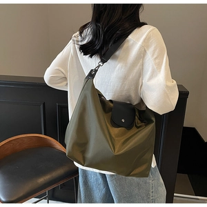 Detail view of army green nylon tote bag with black leather flap on model