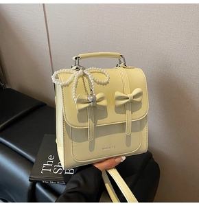 Détail du mini sac à dos en cuir jaune clair avec nœud décoratif et breloque perle