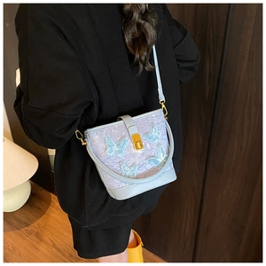Détail du sac seau en dentelle bleue avec ferrures dorées et broderie papillon en 3D
