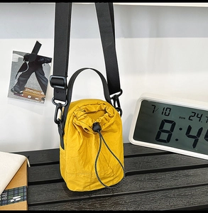 Close-up of yellow drawstring bucket bag with adjustable strap on wooden surface