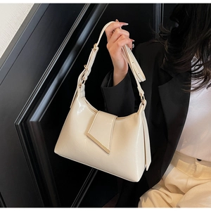 Detail der cremeweißen Lederschultertasche mit Goldverzierung und verstellbarem Riemen
