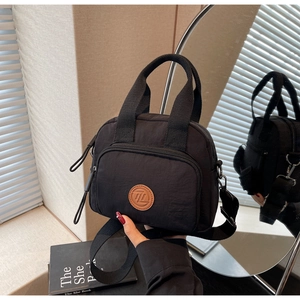 Detailansicht der schwarzen Nylontasche mit Lederlogo und abnehmbarem Schultergurt