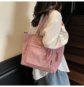 Detail of Morandi pink nylon tote bag featuring cargo pockets and woven rope zipper pulls