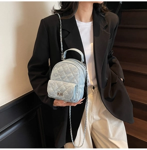 Quilted light blue denim mini backpack with sequins and chain strap on a model
