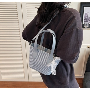 Détail du sac cabas tissé bleu et blanc avec poignée en cuir et nœud en dentelle