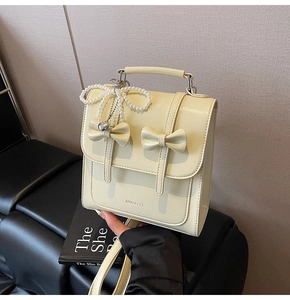 Détail d'un sac à dos rétro jaune crème avec des nœuds en perles et des pendentifs cœurs