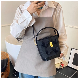 Détail du sac seau noir avec papillons 3D porté en bandoulière pour un look élégant