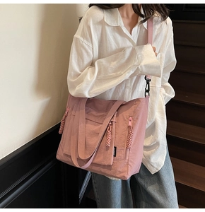 Pink nylon tote bag detail with woven zipper pull and adjustable shoulder strap