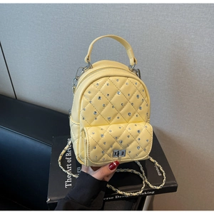 Detail of yellow quilted mini backpack with rhinestone studs and metal chain strap