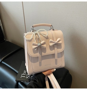 Détail d'un mini sac à dos rose avec doubles nœuds et breloque en perles fantaisie