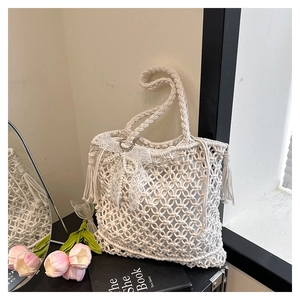 Détail d'un sac macramé blanc avec nœud en dentelle perlée et décorations à franges