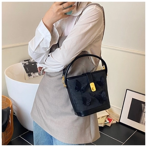 Détail du sac seau noir avec appliques papillons 3D et fermoir en métal doré élégant