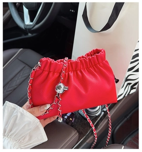 Détail du sac bandoulière plissé rouge avec chaîne argentée et pendentif boule en métal