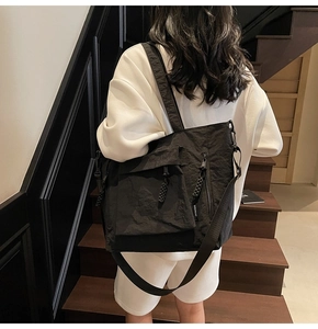 Detailed view of casual black nylon tote bag featuring functional cargo pockets and strap
