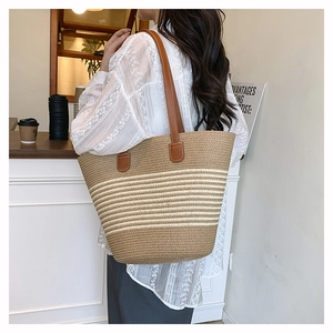 Détail du sac cabas tressé avec lanières en cuir marron et rayures horizontales bicolores