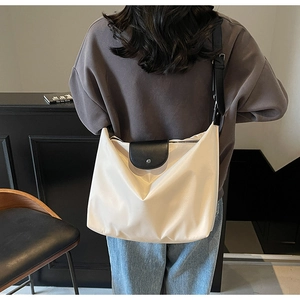 Rear view of model wearing a large cream nylon tote bag with black leather shoulder strap