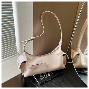 Detail of a light pink glossy leather crossbody bag featuring side pocket and adjustable strap
