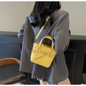 Borsa a secchiello gialla con trama litchi indossata su un blazer grigio