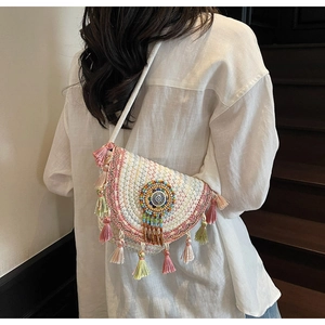 Detail of bohemian semi-circle woven crossbody bag with colorful tassels and beadwork