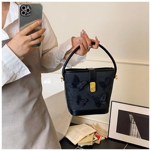 Détail d'un sac seau noir avec d'élégantes broderies papillon et des garnitures dorées